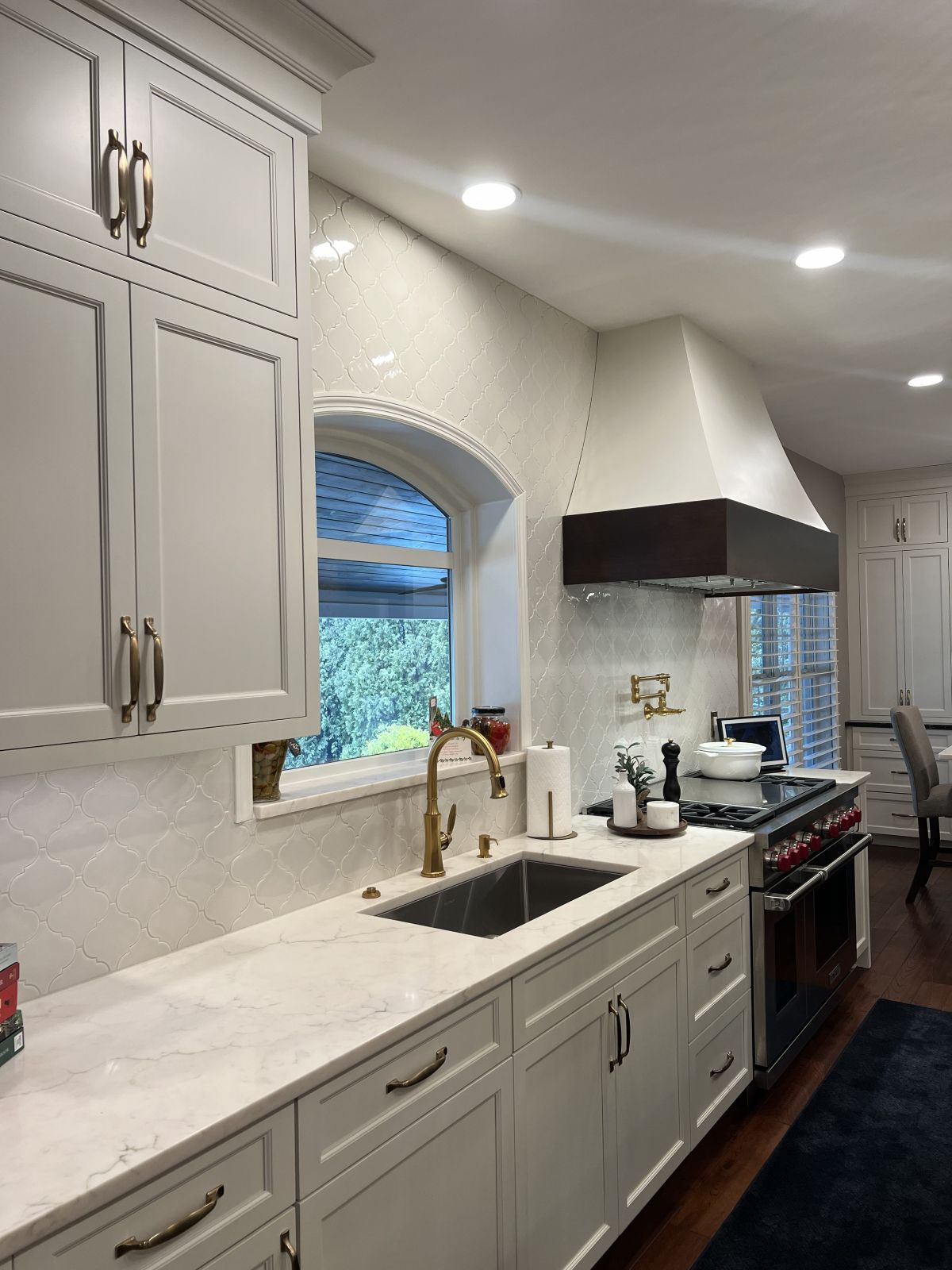 Custom cabinetry, sink, window, and range in a Bella Interiors kitchen