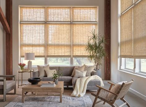 Natural woven wood shades over floor-to-ceiling windows in a bright living room